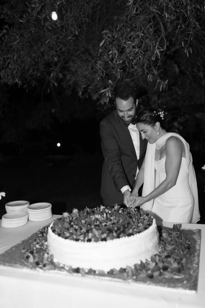 Bride and groom cut cake at one of the best beach destinations in Sicily with dramatic coastal views. 