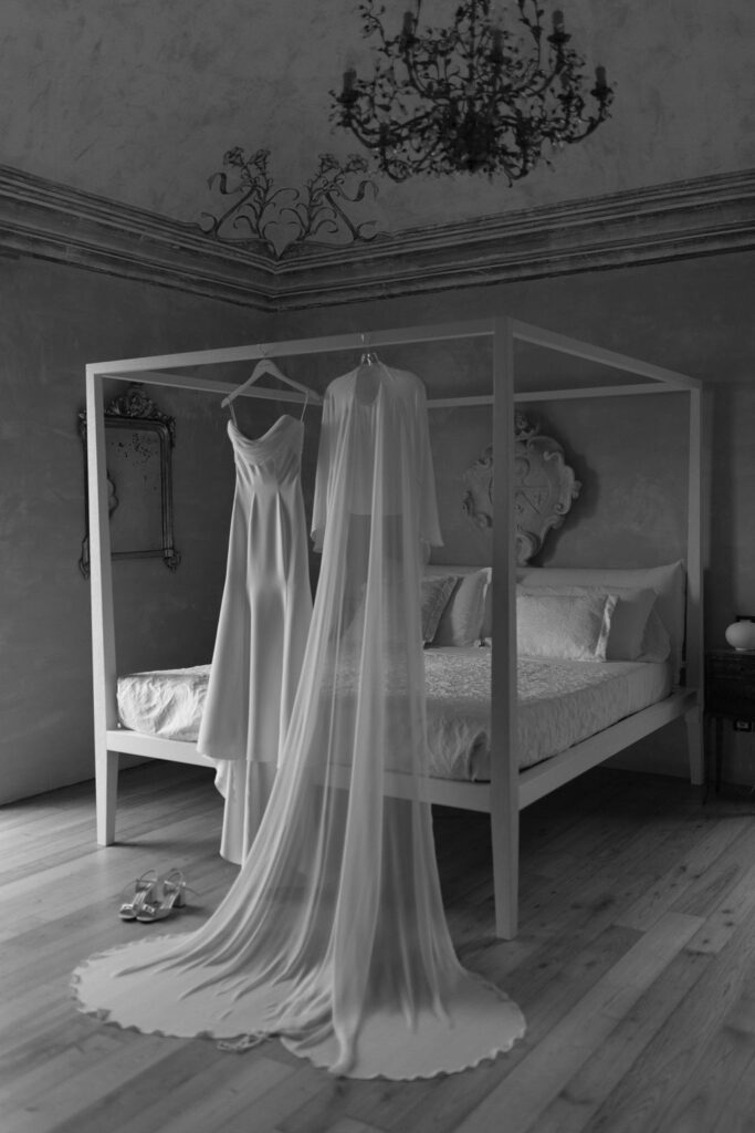 A destination wedding in Sicily set at a historic Italian venue with wedding dress on display on bed post. 