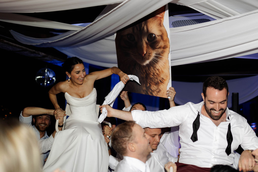 Couple being lifted on chairs at their Monaci delle Terre Nere wedding reception. 