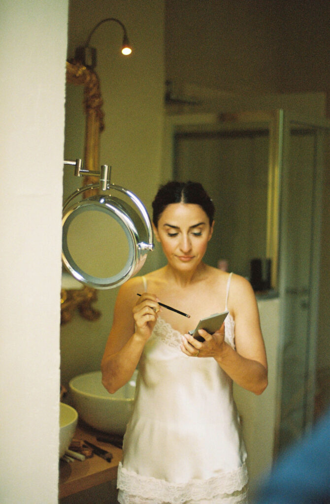 Bride getting ready at elegant Monaci delle Terre Nere hotel grounds overlooking lush gardens in Sicily. 