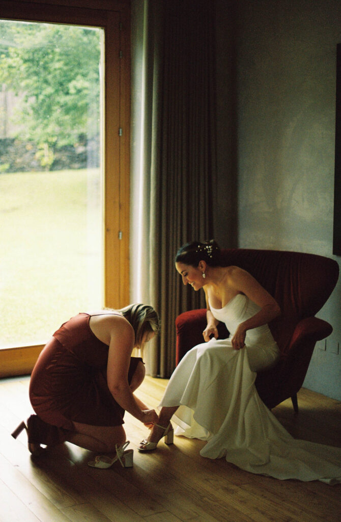 Bridesmaid helps bride put on shoes for her ​Sicily, Italy wedding. 