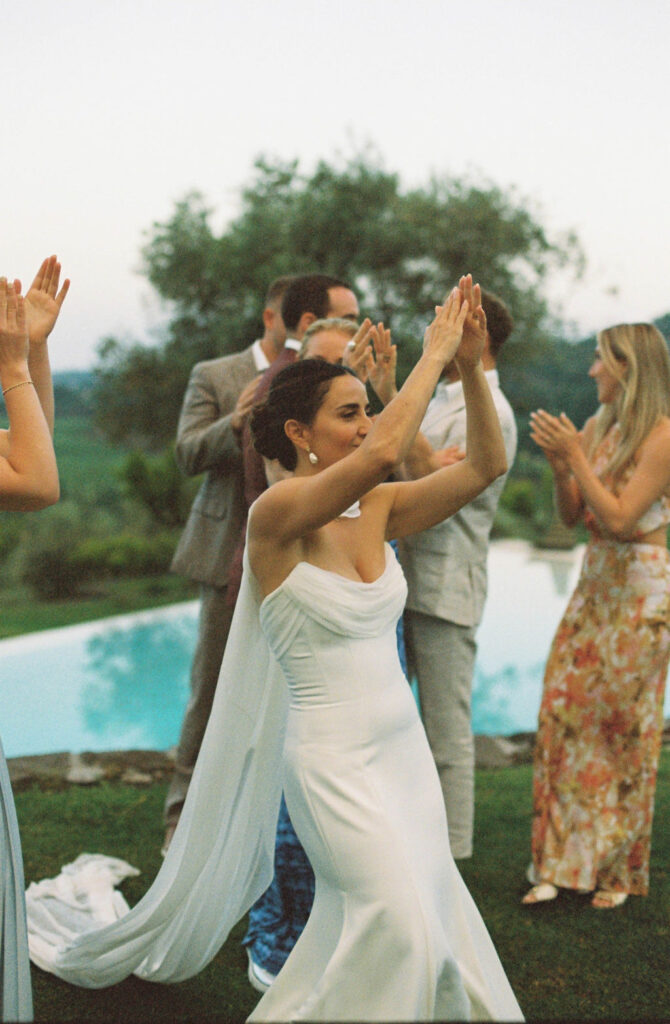 Bride dances with her guests, relaxing after planning a wedding in Sicily. 